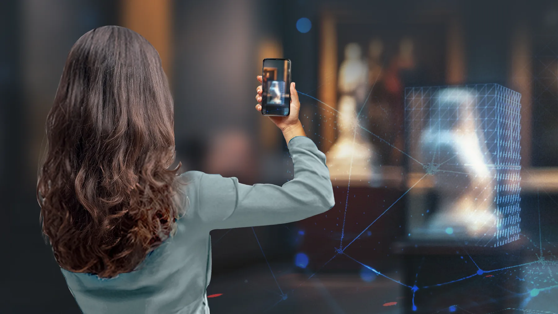A visitor holding up her phone to a statue in a museum gallery